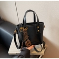 Dettaglio della borsa a secchiello in pelle nera lucida con borchie e ciondoli decorativi - Nero con ciondolo