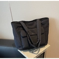 Detalle de un bolso tote acolchado negro con bolsillo frontal de solapa y hebilla de metal - Negro