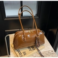 Gros plan sur sac bowling en cuir marron brillant avec zips dorés et breloque fleurie - Avec Pendentif / Marron