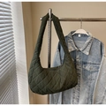 Detailed view of dark olive green quilted hobo bag hanging against a denim jacket - Green