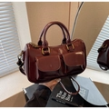 Detailansicht einer burgunderroten Lackleder-Bowlingtasche mit goldenen Vintage-Beschlägen - Burgunderrot