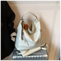 Detail of silver hobo bag with bear charm on a silver suitcase in a minimal setting - Oat With Charm