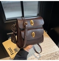 Detailed view of dark brown vintage crossbody bag featuring double gold oval turn-locks - Brown