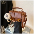 Close-up of retro brown Boston bag with wrinkled leather texture and golden clasp - With Charm / Brown