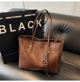 Dettaglio di una borsa tote marrone vintage con ciondolo abaco su un divano in pelle - Con Ciondolo / Marrone