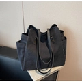 Dettaglio della borsa tote in tela nera con finiture in pelle e tasca laterale su libro - Nero