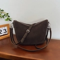 Deep brown suede moon bag with silver zipper and adjustable strap in lifestyle setting - Brown