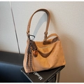 Dettaglio di una borsa tote in pelle scamosciata marrone con tracolla e ciondolo a forma di cioccolato - Marrone con ciondolo