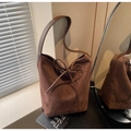 Detailed view of dark brown suede bucket bag texture with decorative bow detail - Coffee