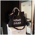 Borsa tote trapuntata nera con ricamo bianco e manici in corda su una scatola - Nero