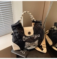 Detalle del bolso tote acolchado con colgante de gato de peluche y asas tejidas - Negro
