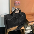 Große schwarze Reisetasche aus mattem Leder mit verstellbarem Schultergurt auf Holzstuhl - Schwarz