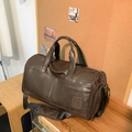 Retro dunkelbraune Leder-Reisetasche mit verstellbarem Gurt auf einem Holztisch - Dunkelbraun