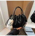 Detail of black pleated bucket bag with shiny finish and cute white puppy plush charm - Black PU With Charm