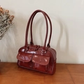 Glossy burgundy Boston shoulder bag with dual front pockets on a wooden surface - No Pendant / Red
