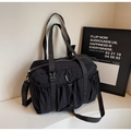 Dettaglio di grande borsa tote in nylon nero con tasche funzionali e moschettone - Nero
