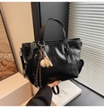 Gros plan d'un sac cabas noir brillant avec un pendentif de baseball et une bandoulière - Noir (Avec Pendentif)