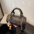 Elegante borsa a mano cilindrica nera con doppi manici e ciondolo in peluche marrone - Nero