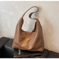 Detail view of brown soft leather tote bag with a golden triangular logo on a black sofa - Khaki