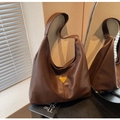 Detail of a dark brown soft leather hobo bag featuring a triangular metal logo plaque - Brown