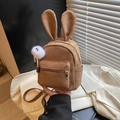 Brown suede backpack with rabbit ears and plush ball charm in a stylish lifestyle setting - With Charm / Brown