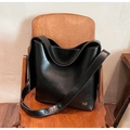 Detalle de bolso en cuero negro mate con logo dorado y correa ancha decorada con tachuelas - Negro