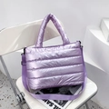 Detailansicht der lila gesteppten Puffer-Tasche mit gepolstertem Griff auf weißem Stuhl - Lila