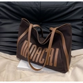 Detail van de grote bruine canvas shopper met lederen handvatten en retro belettering - koffiekleur