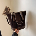 Bolso tipo cubo de gamuza marrón oscuro con asas de cuero y herrajes dorados - café
