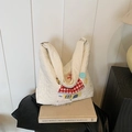 Weiße gesteppte Tragetasche mit Stickerei und flauschigen Pelz-Pompons am Taschenboden - Weiß Typ 2