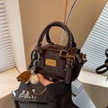 Bolso cilíndrico marrón oscuro brillante con herrajes dorados y dijes deportivos - Con Colgante / Marrón