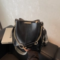 Bolso cubo negro brillante con cadena dorada y correa ancha de jacquard geométrico - Negro