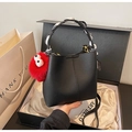 Detail of black lychee grain bucket bag with silk scarf handle and red plush monster charm - Black with Pendant