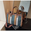 Detalle del bolso de lona a rayas con asas de cuero marrón y correa ajustable - Azul