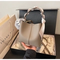 Detailed view of grey bucket bag with scarf-wrapped handle and faux fur pompom charm - Gray With Pendant