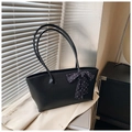 Detalle del bolso de hombro negro con lazo de lunares sobre una chaqueta blanca - Negro