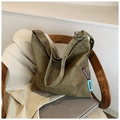 Close-up of military green canvas tote bag with metal eyelet strap and brand label - Green