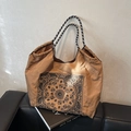 Khakifarbene Paisley-Shopper-Tasche mit gewebten Henkeln auf schwarzem Ledersofa - Braun
