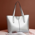 Detalle de un bolso tote plateado metalizado con costuras verticales y asas largas - Plateado