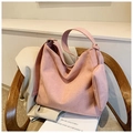 Détail du sac cabas rose en daim dépoli avec petite pochette sur une chaise en bois - Rose