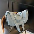 Hellblaue Denim Umhängetasche mit verstellbarem Riemen auf einem Vintage-Ledersessel - Hellblau