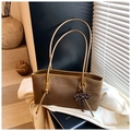 Detail of a brown matte tote bag with thin leather straps and a polka dot bow charm - Brown (With Pendant)