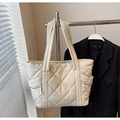 Detail of beige quilted tote bag featuring puffer texture and front zipper pockets - Off White