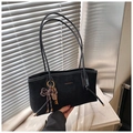 Detail of black suede shoulder bag featuring gold lettering and a brown woven bow charm - Black (With Pendant)