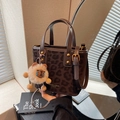 Braune Leoparden-Eimertasche mit Goldnieten und Plüsch-Anhänger in Lifestyle-Szene - Mit Anhänger / Braun