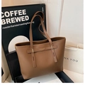 Detail of brown litchi pattern leather tote with gold hardware and fashion lettering - Brown
