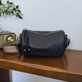 Sac Boston rétro noir avec large bandoulière tissée sur un bureau en bois - Noir