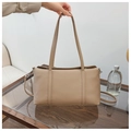 Close-up of beige lychee grain leather texture and shoulder straps on a large tote bag - Khaki