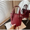 Detalle de bolso cubo de cuero burdeos con herrajes plateados sobre un espejo elegante - Rojo