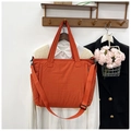 Gesteppte Nylon-Tragetasche mit verstellbarem Schultergurt in einer Lifestyle-Umgebung - Orange